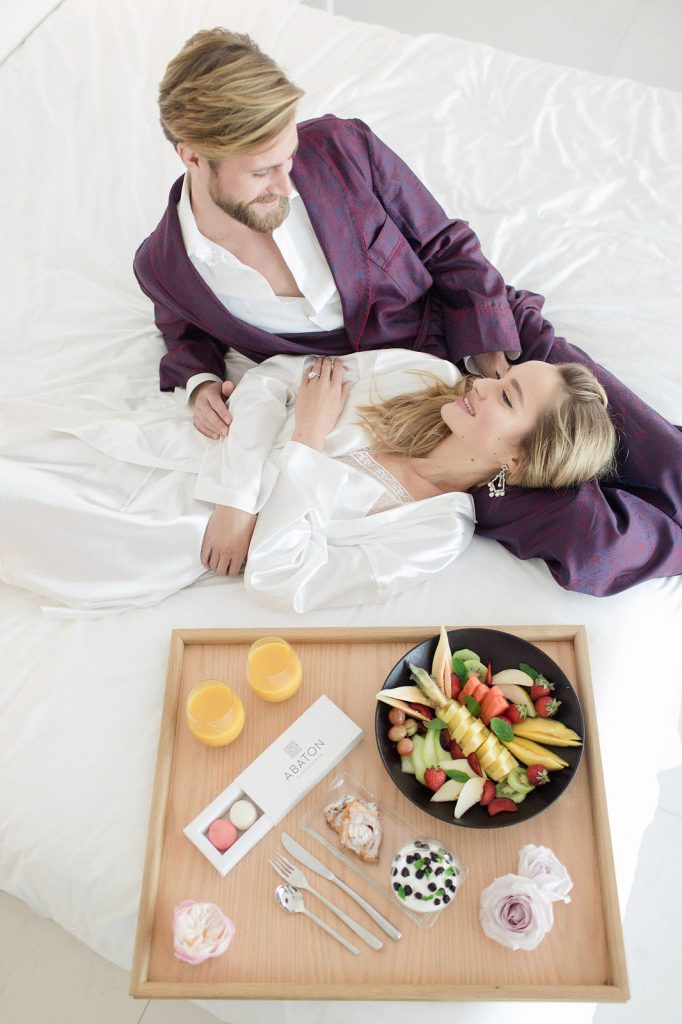 couple laying in bed having breakfast