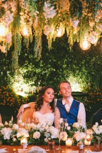 couple on bridal table under a pergola full of foliage
