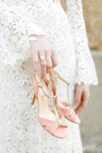 bride holding a pair of pink shoes