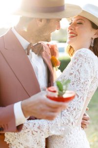 couple in hats laughing and holding a cocktail